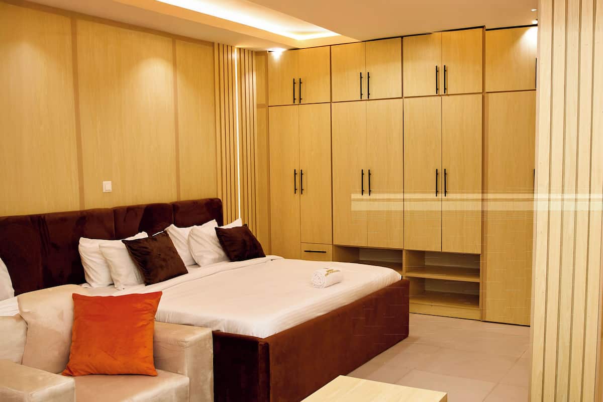 A modern bedroom with a large bed, built-in wardrobe, and a seating area.