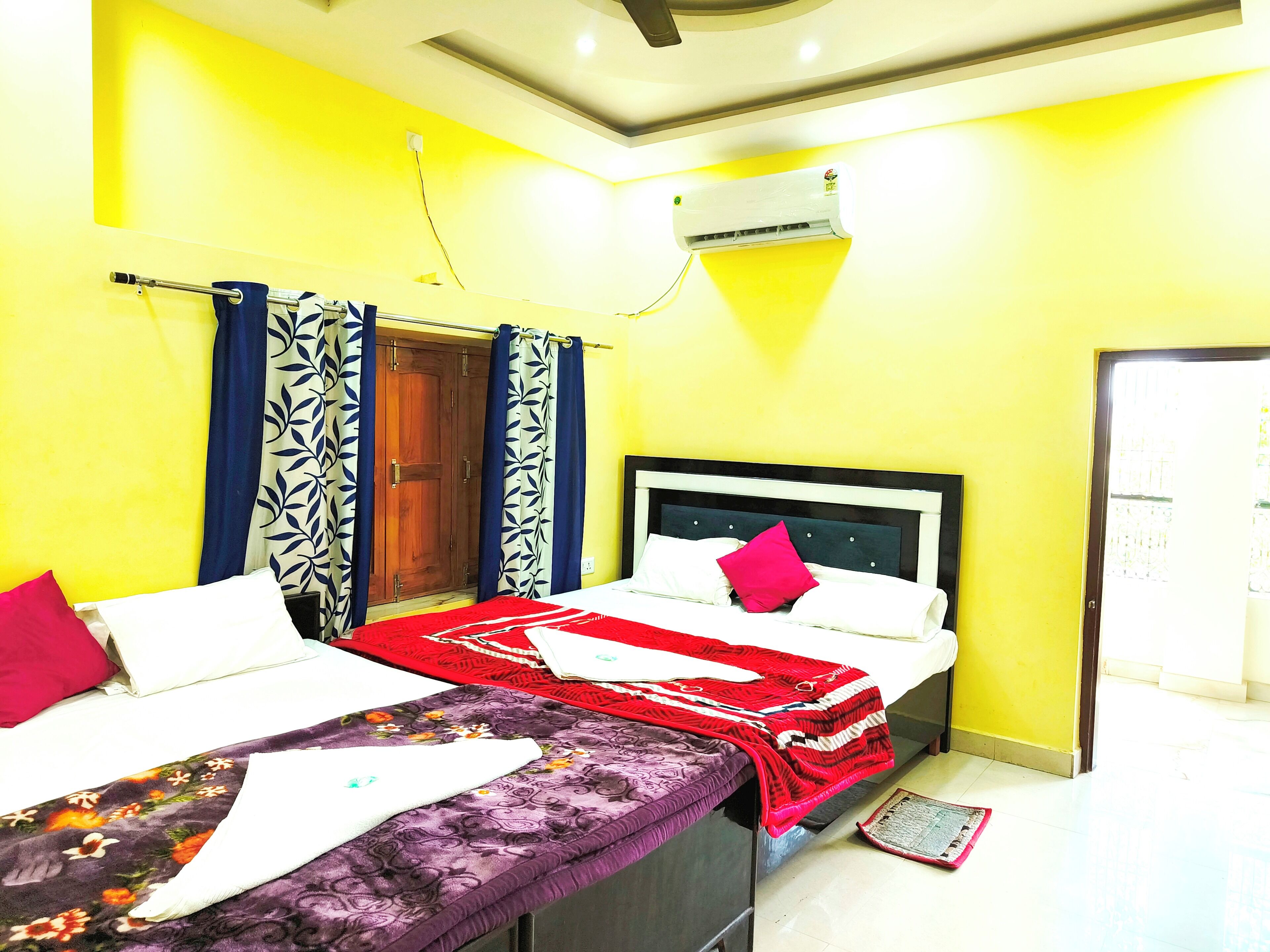 A room with two beds, a wardrobe, and an air conditioning unit.