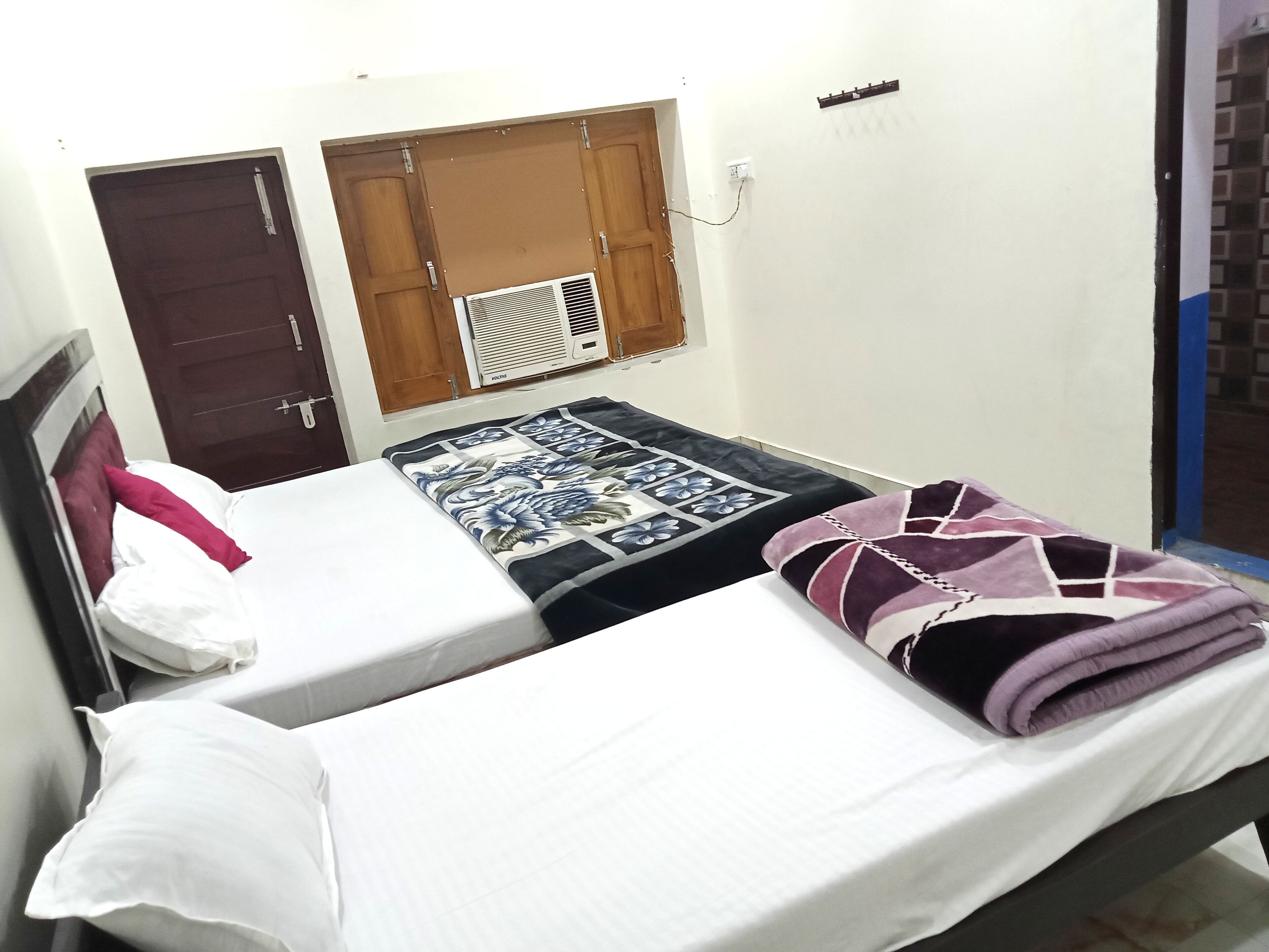 A single bed with a floral bedspread, a white pillow, and a folded blanket.