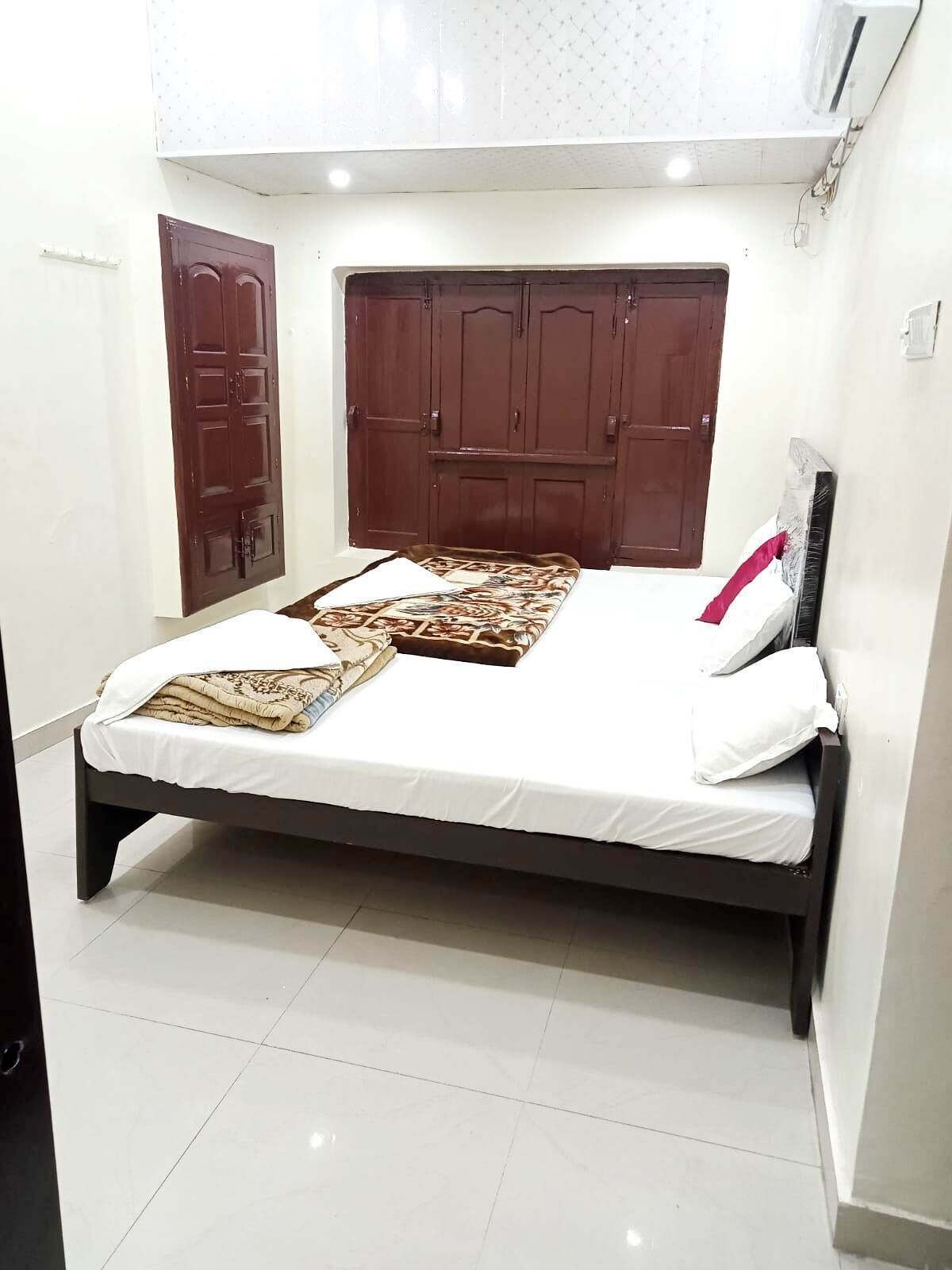 A bedroom with a bed, two wardrobes, a white tiled floor, and a white ceiling.