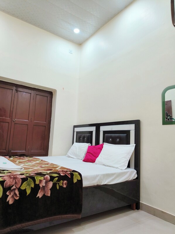 Une chambre à coucher avec un lit, une armoire en bois et un miroir à cadre vert.