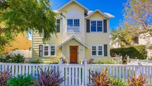 A two-story house with a front porch, a white picket fence, and a variety of plants in the front yard. - Lovely home with backyard oasis & great WiFi - walk to La Jolla Village, dogs OK (La Jolla)