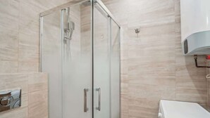 Ein modernes Badezimmer mit einer gläsernen Dusche, einem weißen Waschbecken und einem Handtuchhalter.