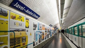 A subway station with advertisements for Citroen and Méhari, and a train on the platform. - Maison Auguste (Paris)