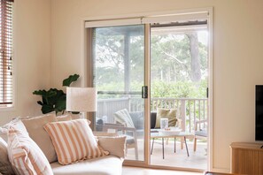 A living room with a sofa, a table, and a TV. - "Treetop Retreat" – Ocean Views & minutes to Beach (MacMasters Beach)