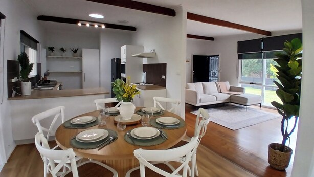 A modern dining area with a round table set for four, surrounded by white chairs. - Capel Sound Hideaway (Capel Sound)