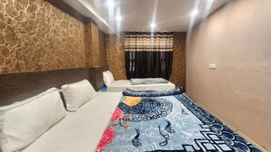 A hotel room with a large bed, a smaller bed, and a nightstand. The room has a marble wall and a ceiling with recessed lighting. - Hotel Swagat Palace (New Delhi)