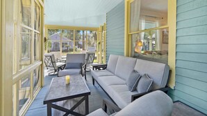 A covered porch with a sofa, chairs, and a table.