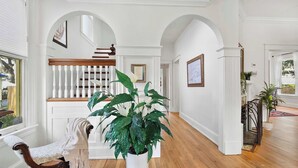 A hallway with a wooden bench, a potted plant, and a staircase.