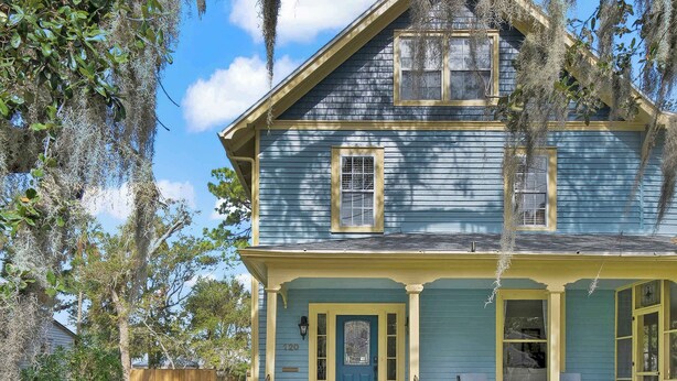 A two-story house with a front porch, a brick entryway, and a number '120' on the door.