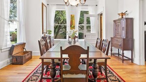 A dining room with a large wooden table, chairs, and a chandelier.