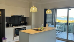 Een moderne keuken met een centraal eiland, roestvrijstalen apparatuur en hanglampen.