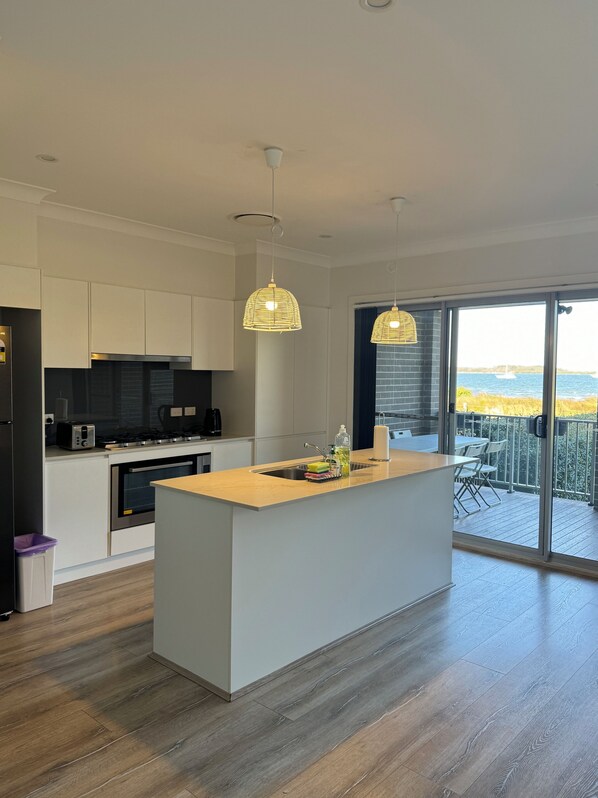Una cocina moderna con una isla central, electrodomésticos de acero inoxidable e iluminación colgante.