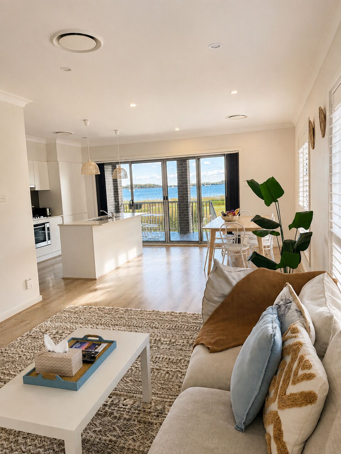 Un salon moderne avec un canapé, une table basse et une vue sur un balcon aménagé en coin repas.