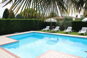 A swimming pool with white lounge chairs and a tiled deck. - Ferienwohnung mit Terrasse und Pool (Lazise)