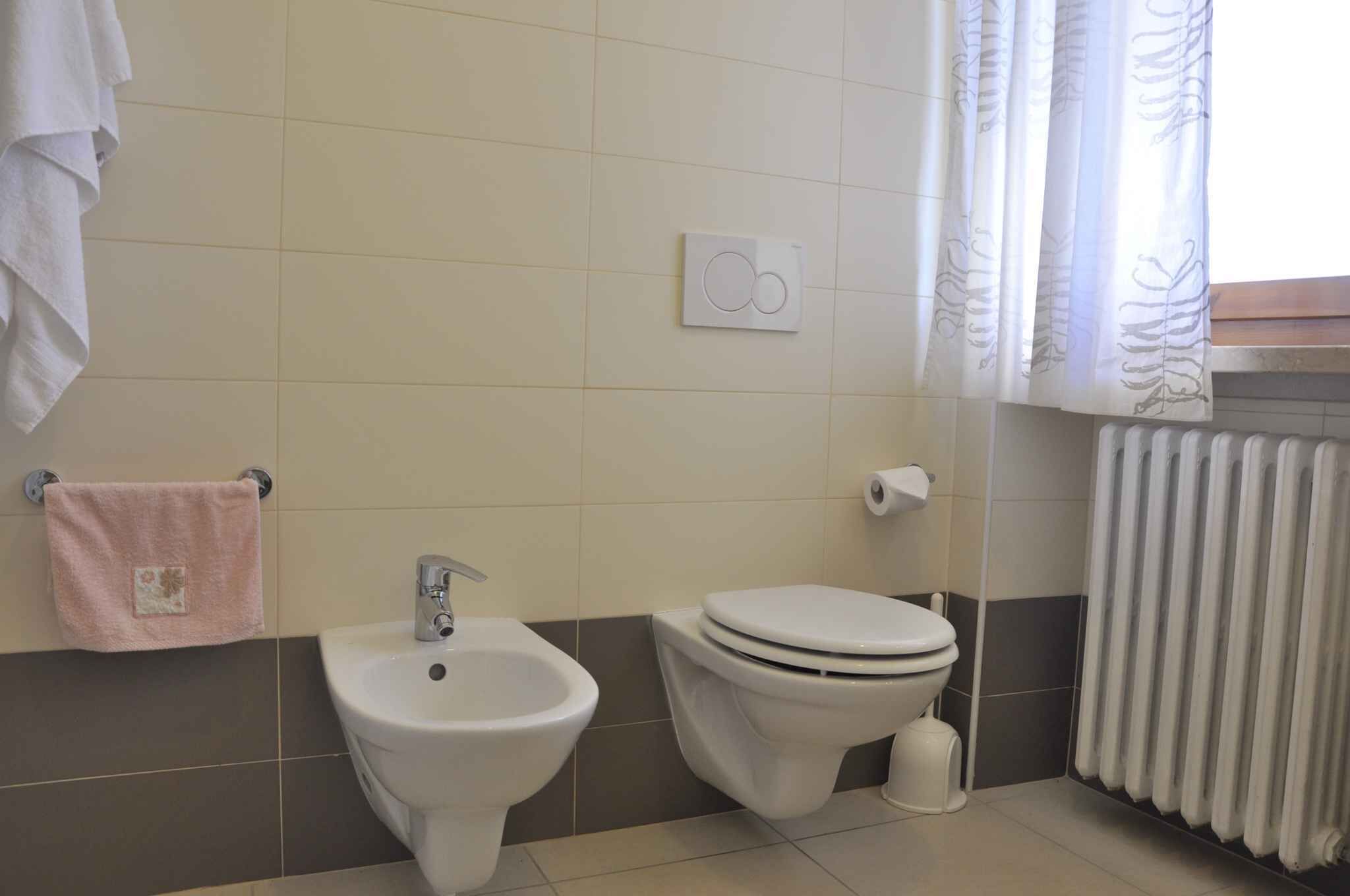 A bathroom with a bidet, toilet, and a towel rack.
