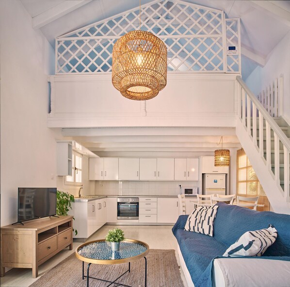 A spacious living area with a loft bedroom, a kitchen, and a dining area.