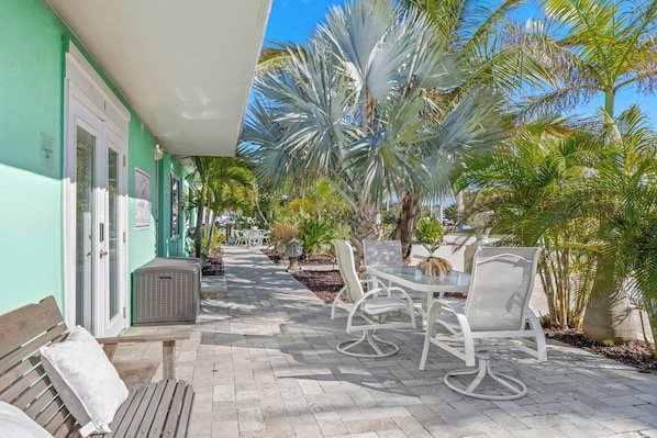 Une terrasse avec des siÚges extérieurs, des palmiers et un bùtiment à la façade verdoyante.