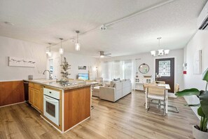 A modern kitchen with a central island, wooden cabinets, and a built-in oven.
