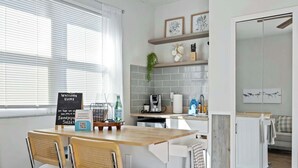 A modern kitchen with a dining area, a signboard, and a view of the living room. - Sandpiper Studio | Across From Beach! (Satellite Beach)