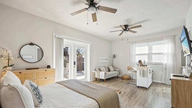 A bedroom with a bed, bedside tables, a dresser, a ceiling fan, a window, and a TV. - Sandpiper Studio | Across From Beach! (Satellite Beach)