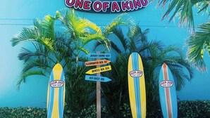 A Ron Jon Surf Shop sign with surfboards and directional signs. - Sandpiper Studio | Across From Beach! (Satellite Beach)