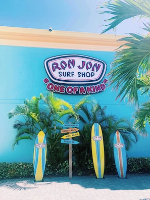 Ron Jon Surf Shop -liikkeen kyltti, jossa on surffilautoja ja opasteita.