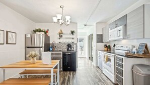A modern kitchen with stainless steel appliances, a wooden dining table, and a black dishwasher.
