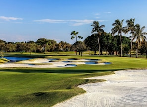 A golf course with sand bunkers, a pond, and palm trees. - Restoration Hardware PGA National Gated Community by Guaranteed Rental™ (Palm Beach Gardens)