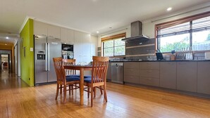 Une cuisine moderne avec des chaises en bois, une table à manger et une grande fenêtre.