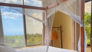 A bed with a canopy, a view of the outdoors, and a clothing rack. - Authentic Mikoko Beach & Cottages (Bagamoyo)