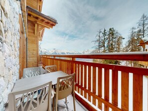 A wooden balcony with a table and chairs, overlooking a snowy mountain landscape. - Apartment in Ski In Ski Out Location (Veysonnaz)