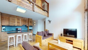 A modern loft-style living space with a kitchen, a dining area, and a seating area with a sofa and a TV. - Apartment in Ski In Ski Out Location (Veysonnaz)