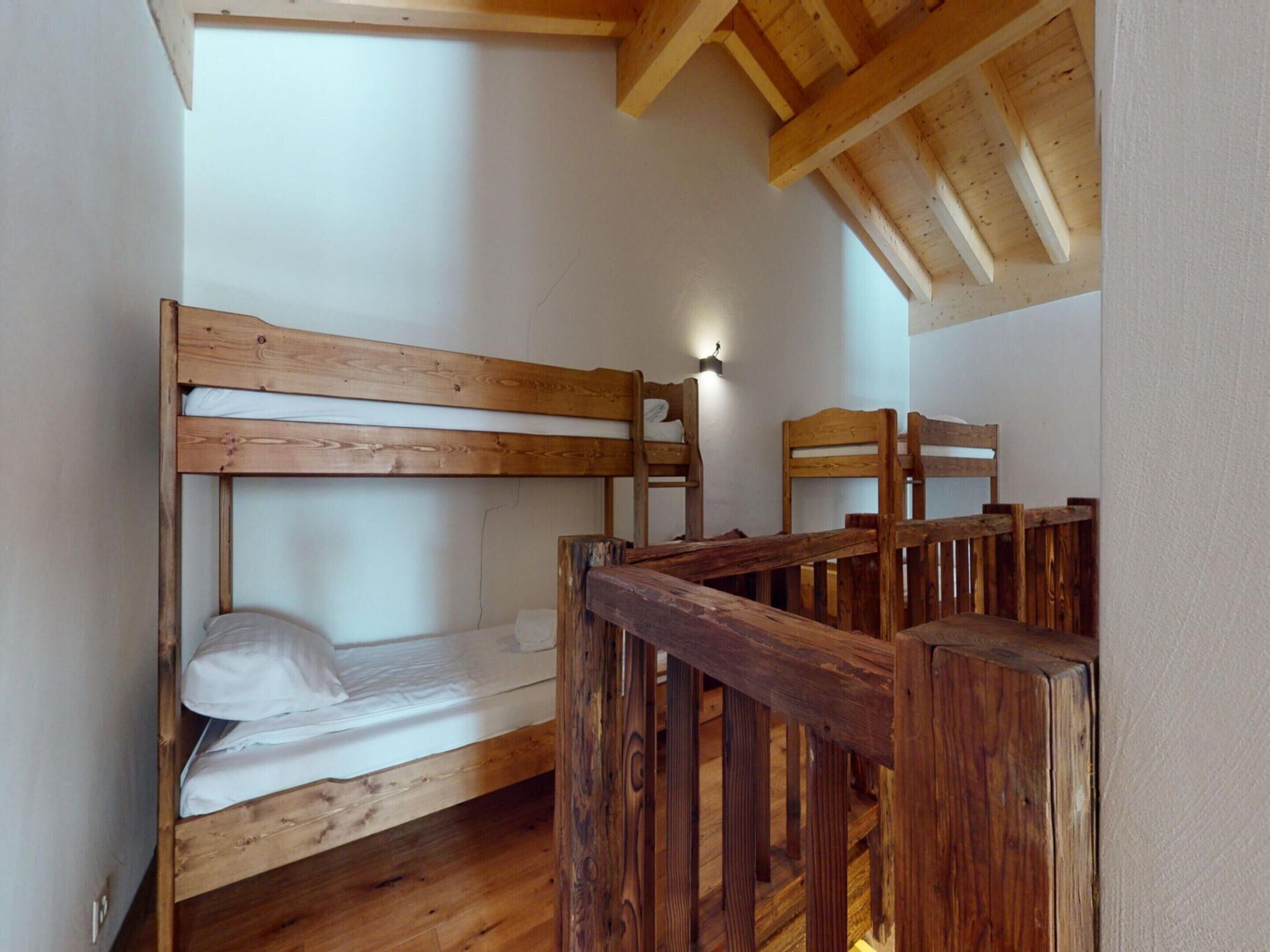 A room with a bunk bed and a wooden chair.