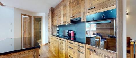A modern kitchen with wooden cabinetry and black countertops.