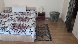 A bed with a floral bedspread, a bedside lamp, a small rug, and a nightstand. - 2 Bed Appt-balcony-pet Friendly-city Centre (Focsani)