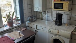 A compact kitchen with a washing machine, a microwave, and a coffee maker. - 2 Bed Appt-balcony-pet Friendly-city Centre (Focsani)