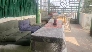 A room with a sofa, a table with a lace tablecloth, and a chair. - Via Ganga View (Varanasi)