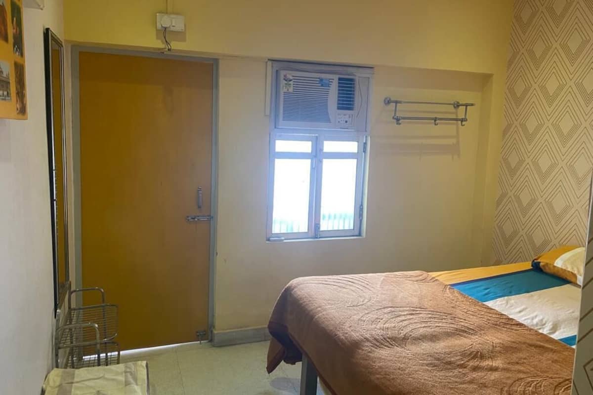 Un dormitorio con una cama, una ventana con persianas, un radiador y una puerta.