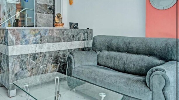 A modern living room with a grey sofa, a glass coffee table, and a marble reception desk. - Via Ganga View (Varanasi)