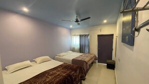 A room with two beds, a ceiling fan, and a door. - Via Ganga View (Varanasi)