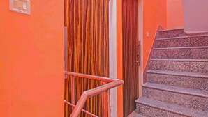 A staircase with a handrail leading to a door with vertical stripes. - Hotel Ram Palace (New Delhi)