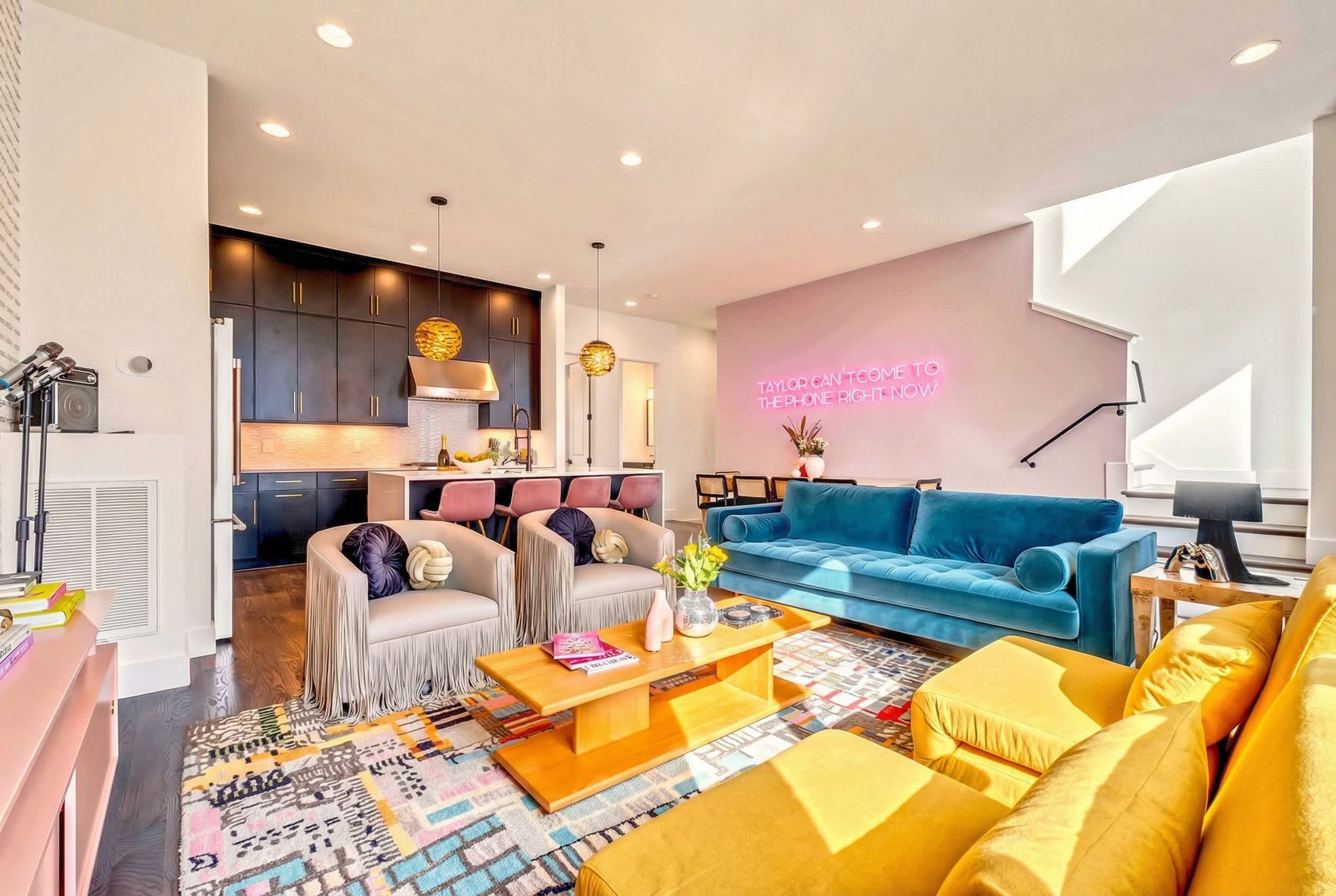 A modern living room with a blue sofa, yellow armchairs, a wooden coffee table, and a patterned rug.