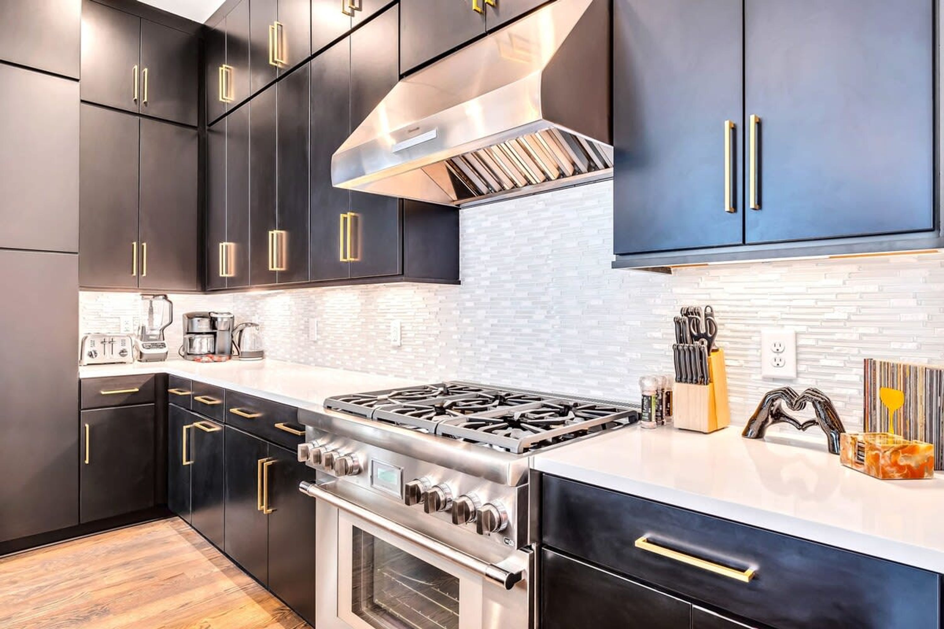 A modern kitchen with dark cabinetry, stainless steel appliances, and a white countertop.