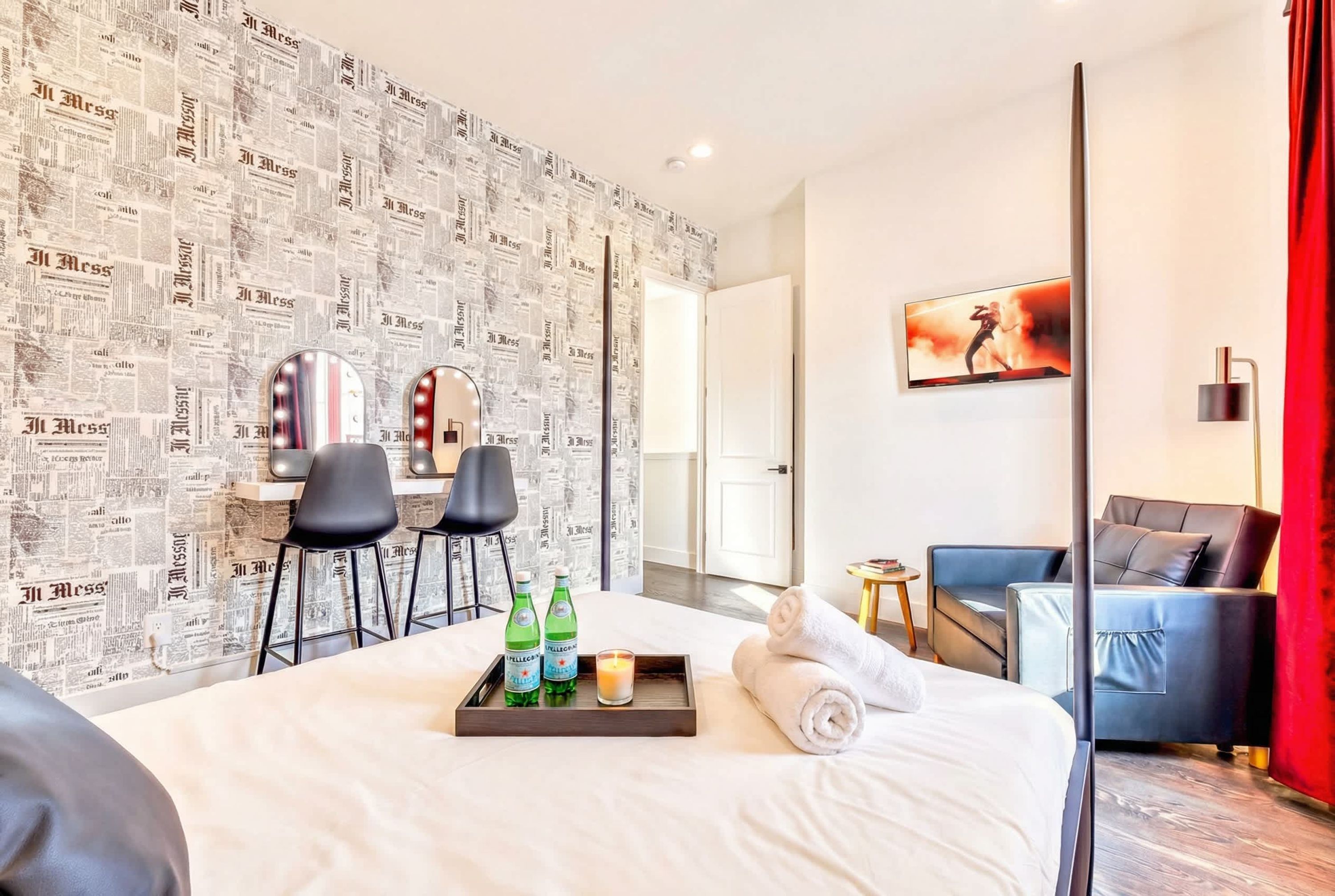 A hotel room with a bed, a desk with two chairs, a TV, and a sofa.