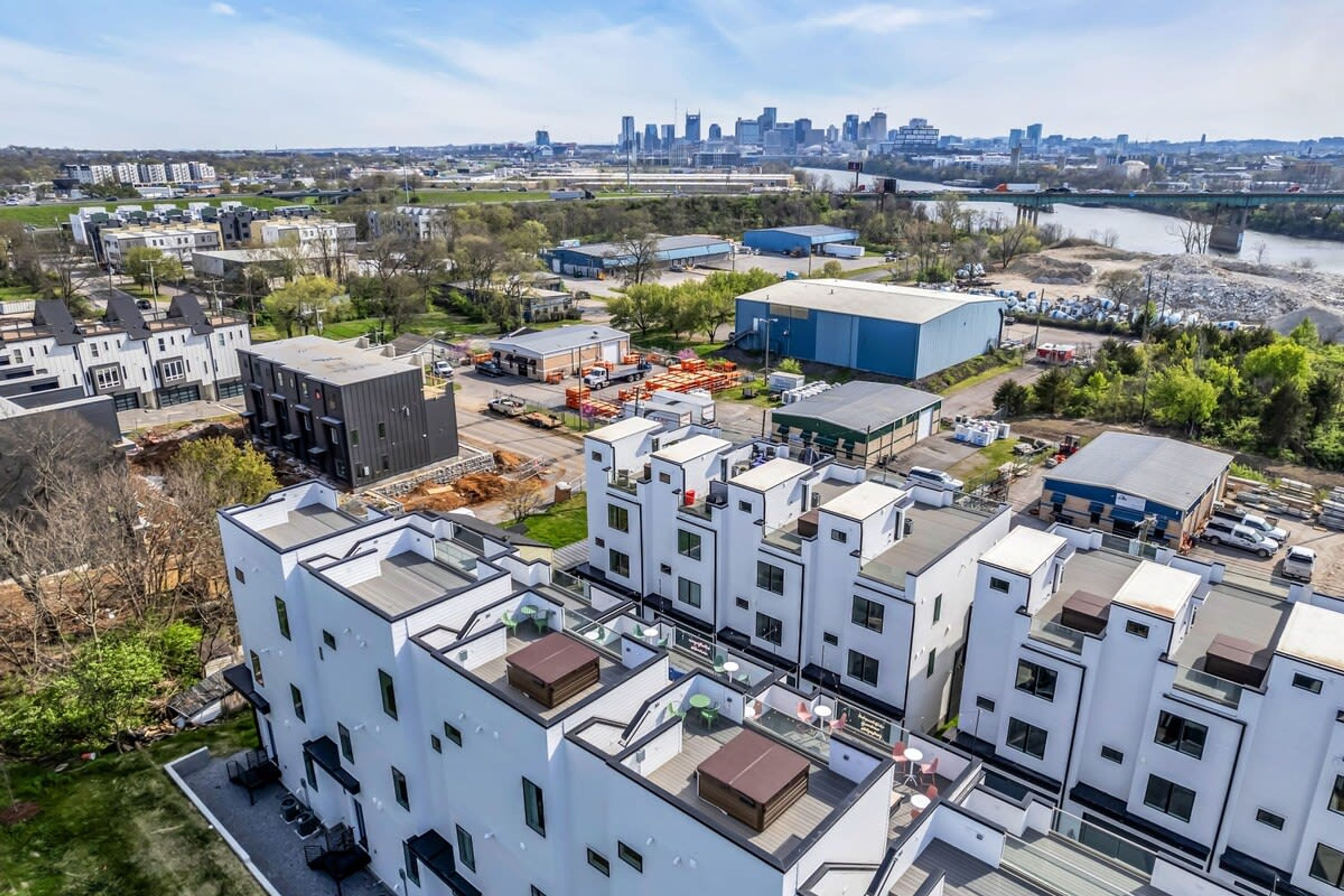A modern residential area with white buildings, a large blue warehouse, and a river in the background.