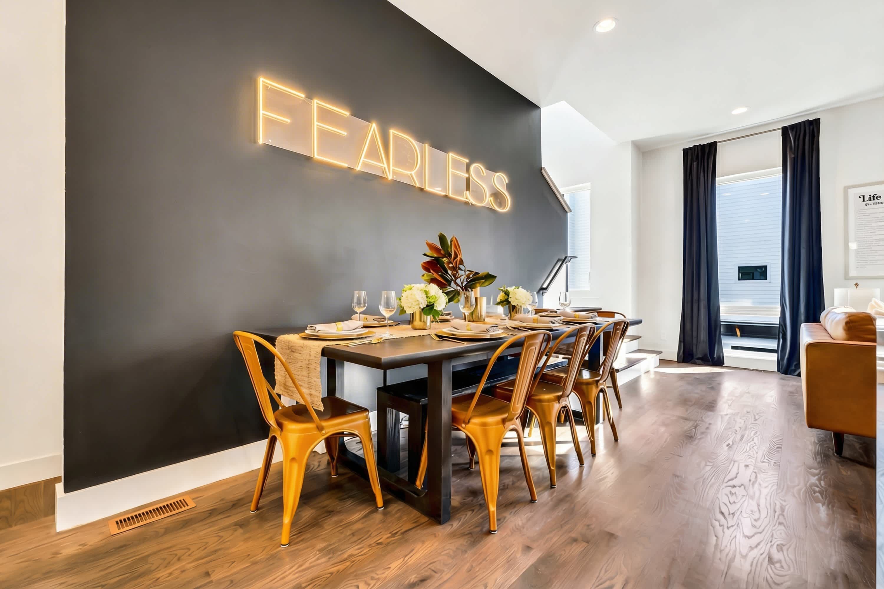 A modern dining area with a black wall and a neon sign that reads "FEARLESS."