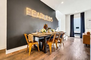 A modern dining area with a black wall and a neon sign that reads "FEARLESS." - Luxury Stay With Rooftop Views in Prime Location (Nashville)