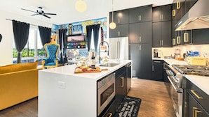 Una cocina moderna con armarios oscuros, una isla central y vistas al exterior.