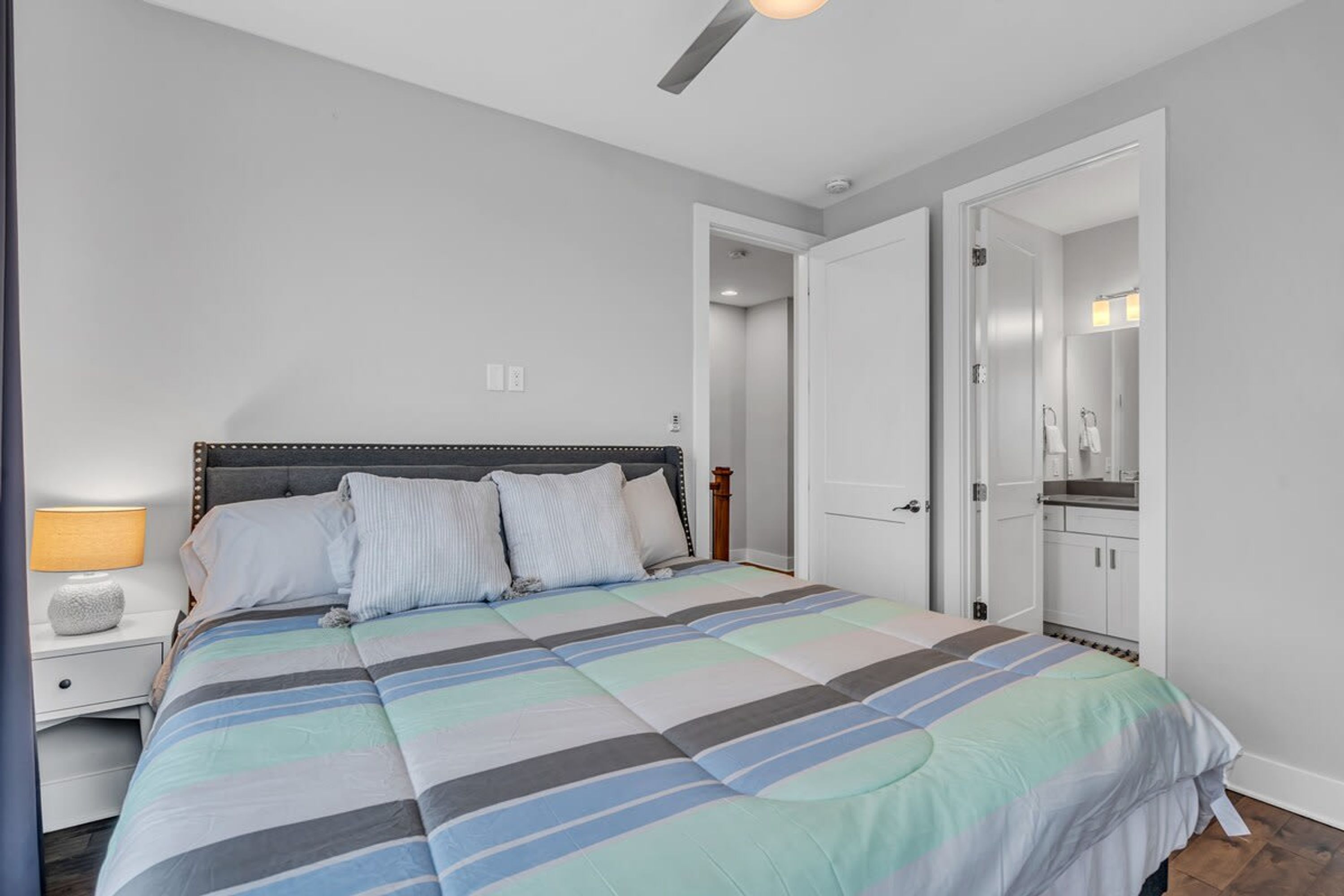 Een slaapkamer met een bed, nachtkastje en een badkamer die door een open deur zichtbaar is.